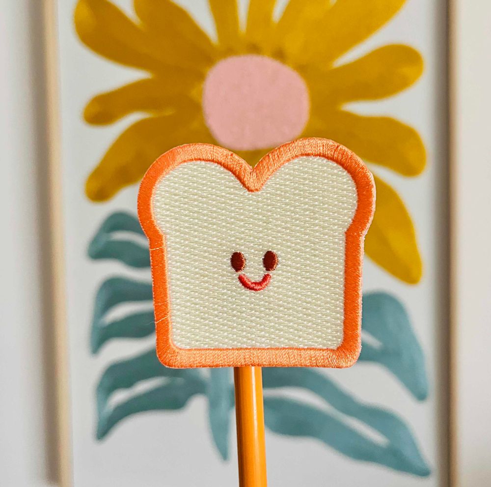 an embroidered patch of a smiling bread slice. 