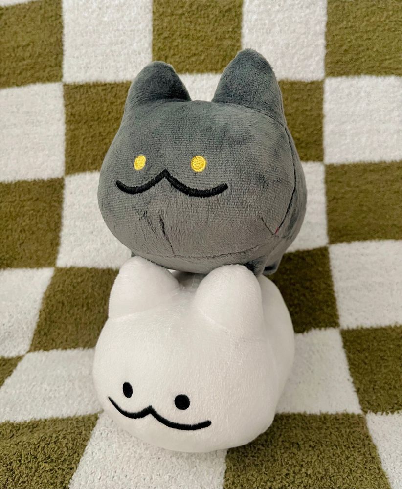 the same white cat plush with a black cat version stacked on top of her.