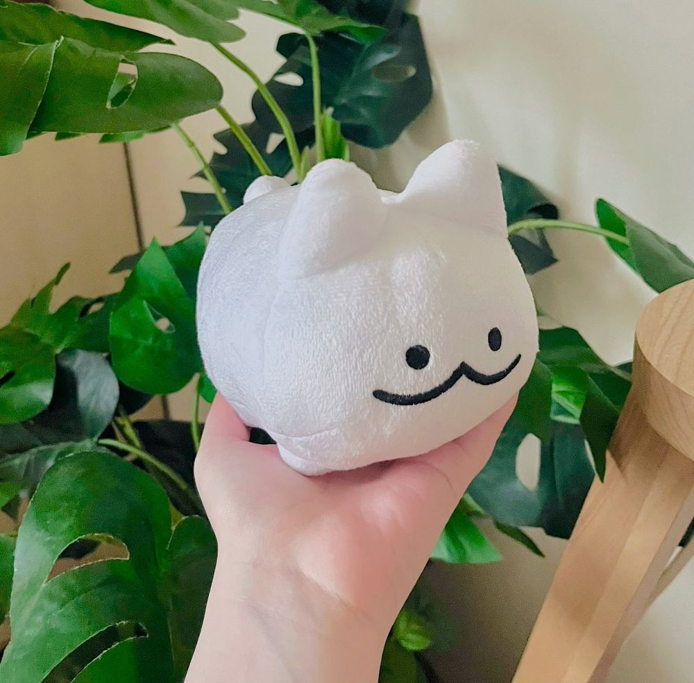a little white cat plush with a cute smiling face. 