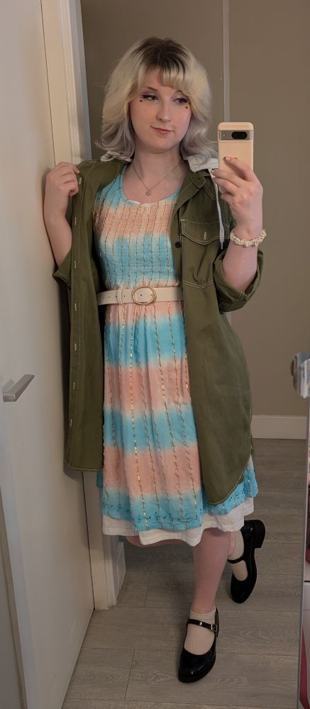 A mirror selfie of Gwebulls wearing a dress that has the same pink/blue/white colours as in the trans flag