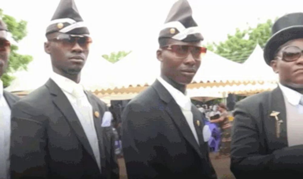 a group of men wearing black suits and hats are standing in a line