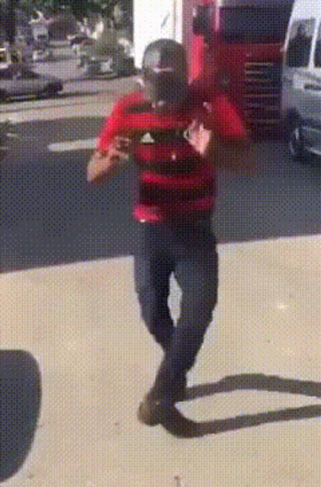 a man wearing a red and black adidas shirt is walking down the street