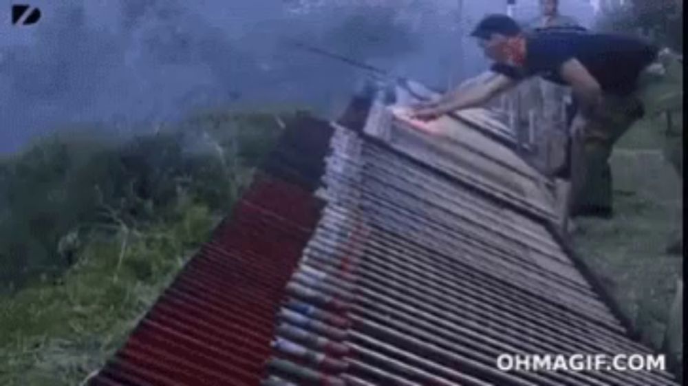 a man is standing on top of a metal fence with a flame coming out of it .