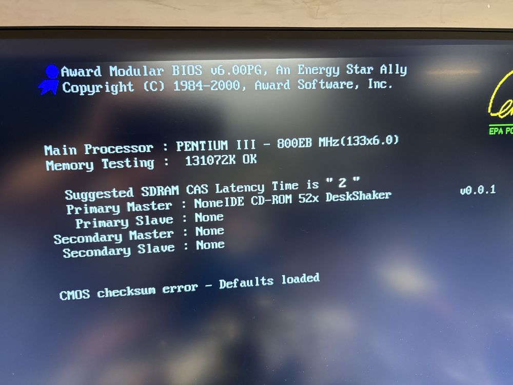A photo of a monitor showing a PC BIOS screen from a system with a Pentium III CPU. In the area where it detects drives, it shows: "Primary Master : NoneIDE CD-ROM 52x Desk Shaker              v0.0.1"