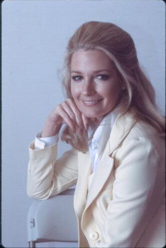 Deidre Hall in the late 1970s, seated with effortless poise in a pale blazer and crisp white blouse. Her hand rests thoughtfully against her chin, capturing a moment of quiet glamour. A radiant portrait from the early days of Marlena Evans — and an early sighting of the soap opera blazer era.