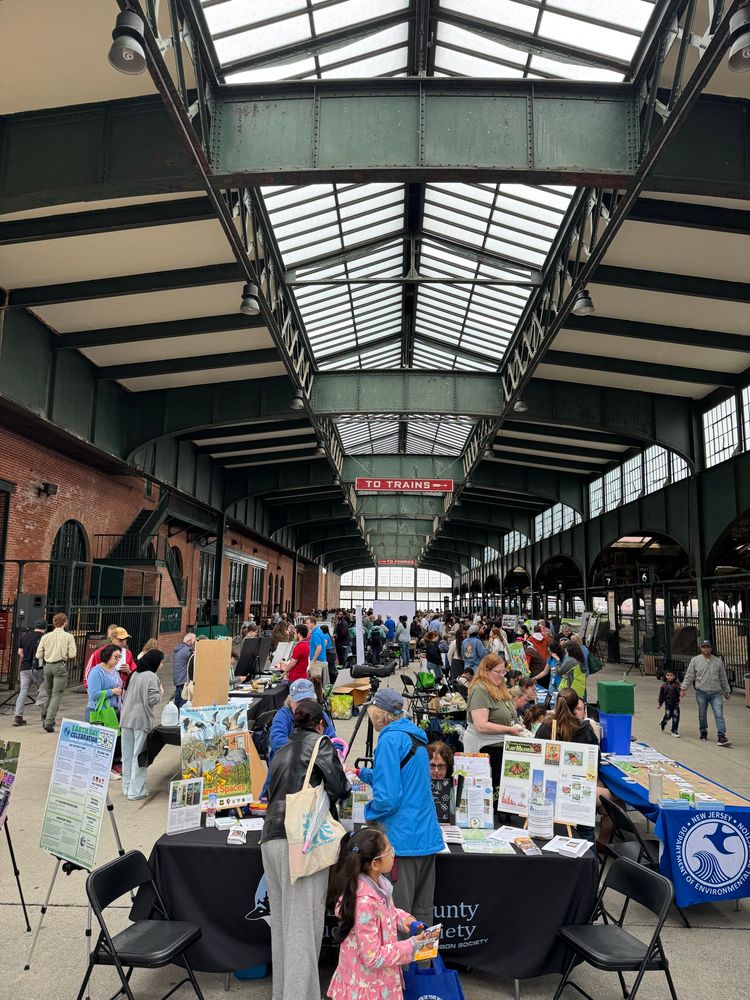 People, information tables, and activity inside the Liberty State Park historic marine terminal.