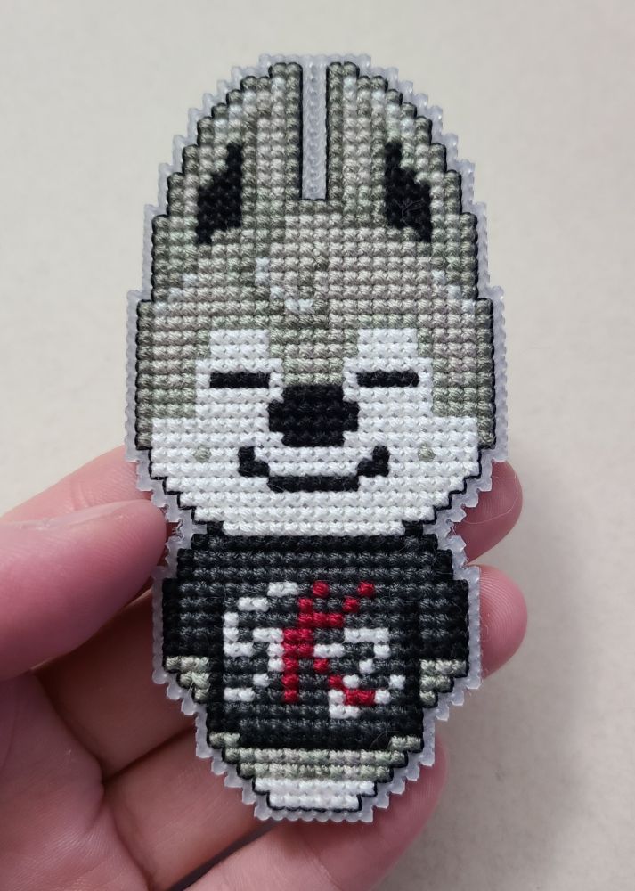 A cross stitch wolf character with a black shirt that says SKZ