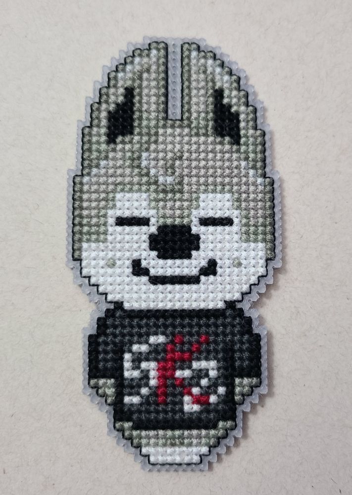 A cross stitch wolf character with a black shirt that says SKZ