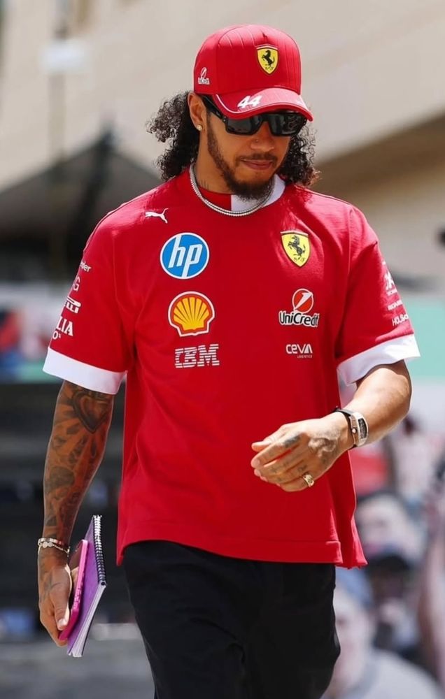 Lewis arrives in Sakhir in a Ferrari team shirt and cap. He has let his braids out and I want to see his hair in all its glory.