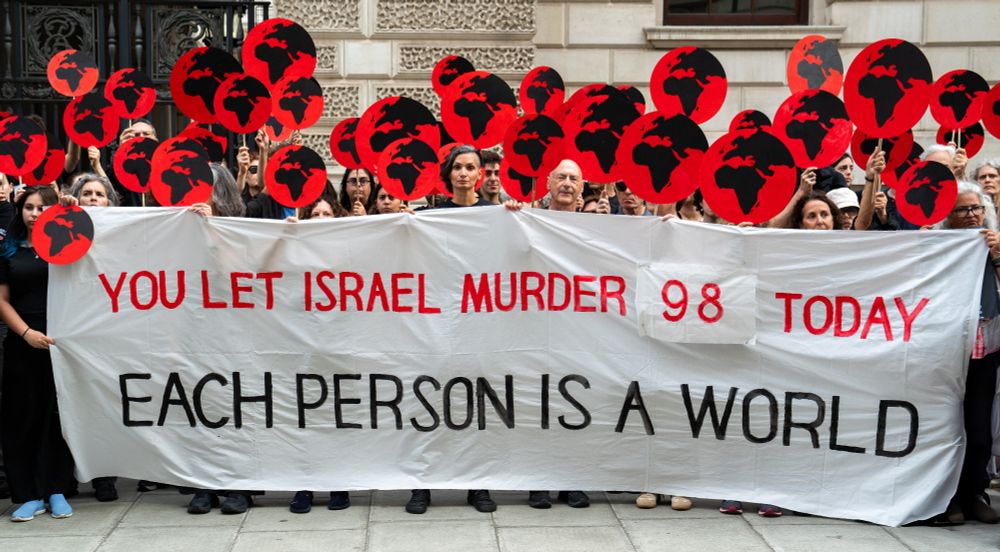 Protestors holding globe signs and the slogan 
You let Israel murder 98 today / Each Person is a world
Credit: Lia Na'ama Ten Brink / Mi-neged