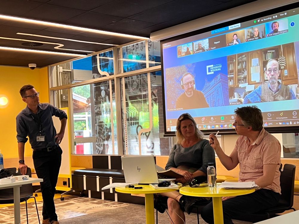 Tom Cochrane talking to Eva de Hullu and Warren Mansell in the room, and Andreas Eder and Bruce Nevin online for a symposium on emotion.