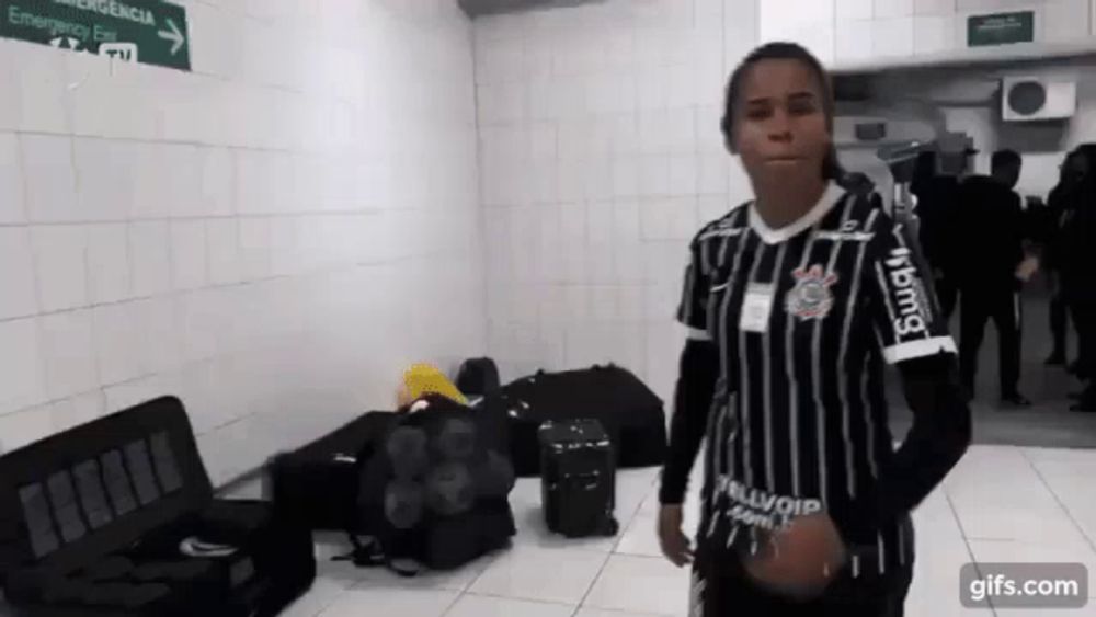 a woman wearing a corinthians jersey is standing in a hallway