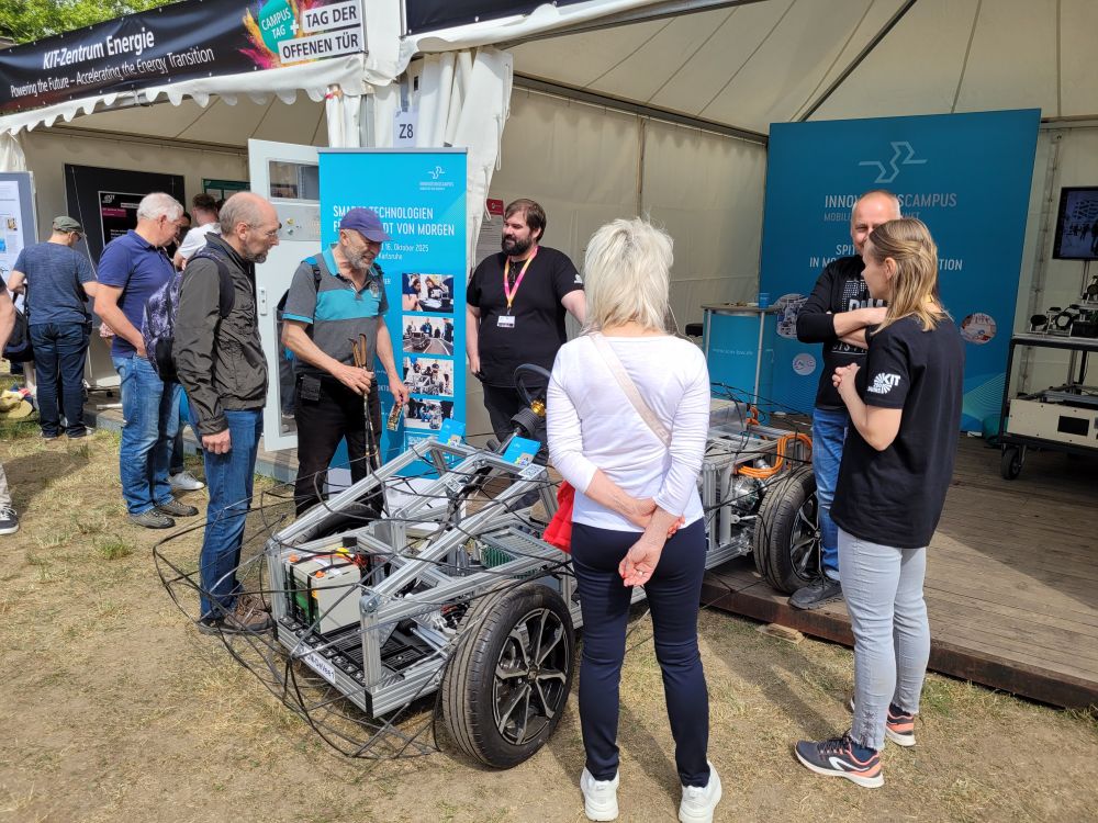 Mehrere Personen stehen um ein Fahrzeug am Stand des InnovationsCampus Mobilität der Zukunft. 