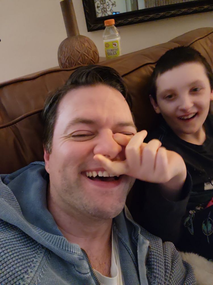 My son lovingly pinching my nose while I am laughing