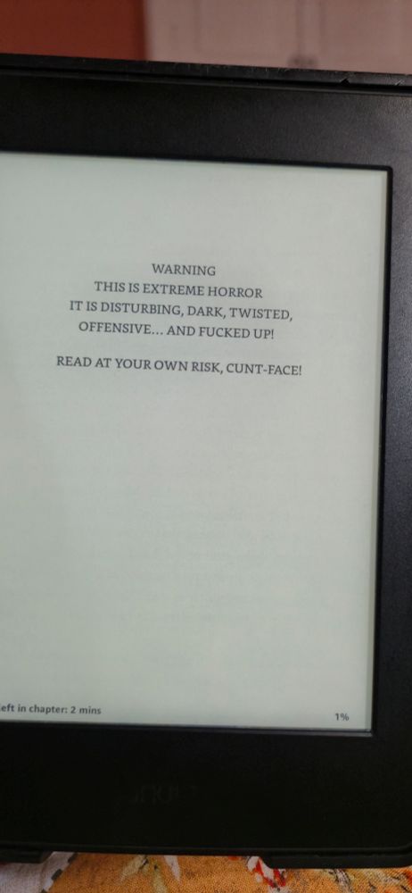A kindle screen that reads " warning. This is extreme horror. It is disturbing, dark, twisted, offensive... and fucked up! Read at your own risk, cunt face!"