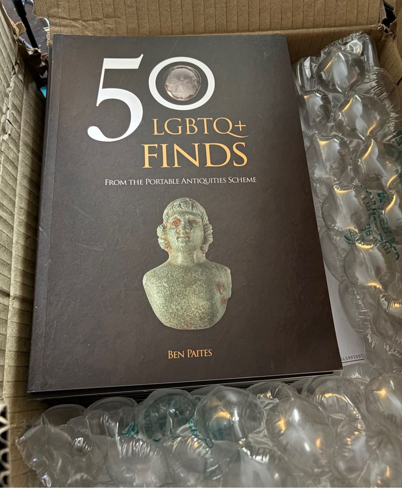 A stack of books in a cardboard box with large bubble wrap packing them in. The book is 50 LGBTQ+ Finds.