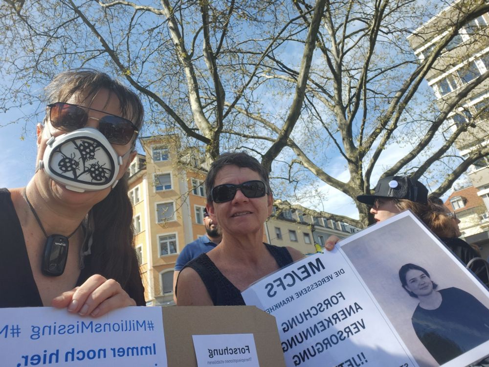 Selfie. Zwei Frauen mit Plakaten um auf MECFS aufmerksam zu machen. Auf einem ist die betroffene Tochter abgebildet.