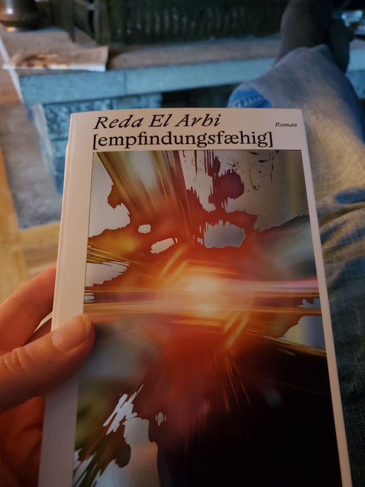 Eine Hand hält das Buch 'empfindungsfähig' von ElArbi