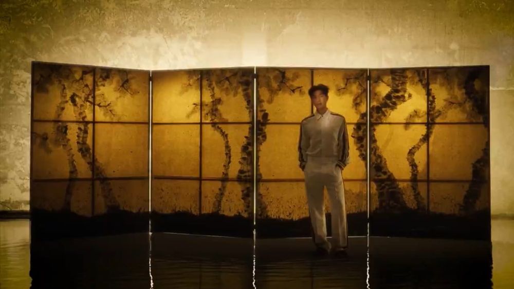 namjoon for bazaar, standing in front of a golden mural in an all white outfit