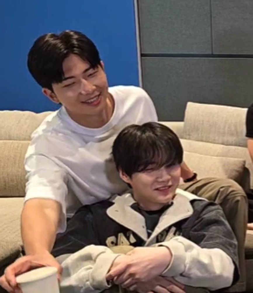 yoongi lying against namjoon's legs with namjoon's hands on his shoulders 
