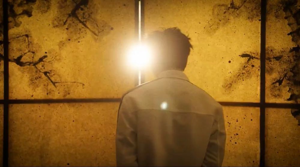 namjoon for bazaar, his back facing us while he faces the golden mural and light comes from a small separation 