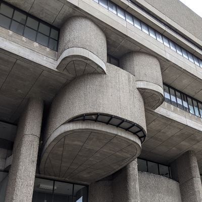 The underside of a stairwell at the Lindeman Center in downtown Boston. The Brutalist concrete building's stairwells stick out from the facade in a way that looks like a frog making a 😬 face.