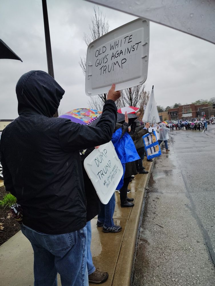 A person holds a sign that reads "Old white guys against Trump"