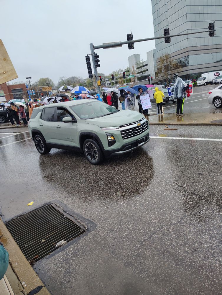 Lines of people demonstrating at a busy intersection of St. Louis 
They are yelling Hands Off!