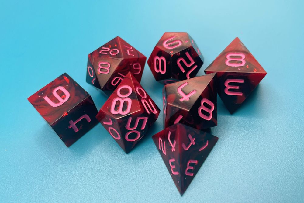 A 7 piece dnd set on a blue background. The dice are swirled with red and black with pink numbers.