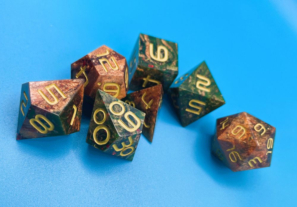 A 7 piece dnd set on a blue background. The dice are swirled with green and copper, with gold yellow numbers.