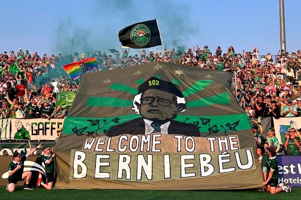 a tifo displayed by fans of Vermont Green FC in their stadium in Burlington during their match against Ballard which secured their victory in the second tier of the USL.  The tifo shows a portrait of Bernie Sanders, against the backdrop of a rising green sun, and the slogan "Welcome to the Berniebéu"