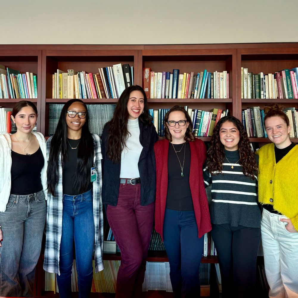 Six smiling team members of The MATTERS Lab standing in front of books. 