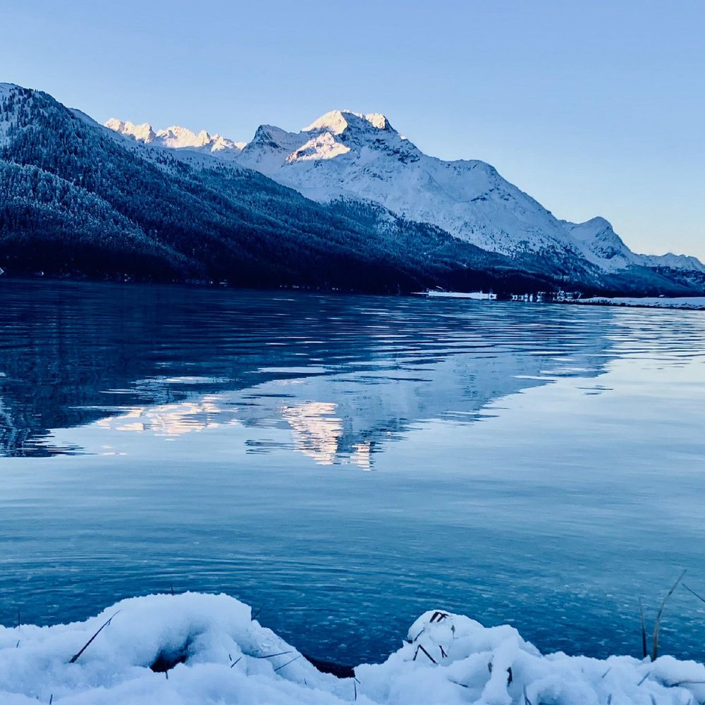 a snowy mountain next to a body of water