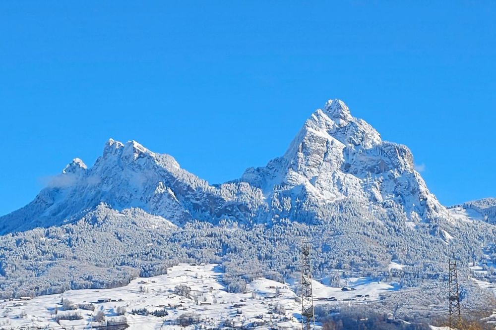 Majestic snow-capped mountains dominate the landscape, with a small town nestled in the valley below.