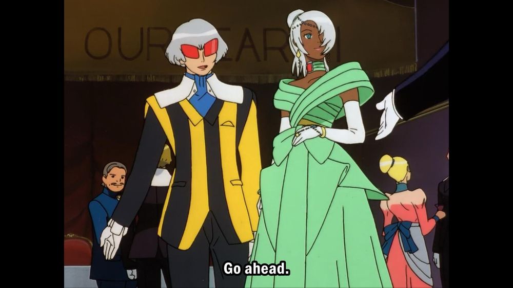Harry and Laura from Turn A Gundam looking like the lovable idiots they are. Harry in a black and yellow pinstripe suit with a blue ascot and his fuckass red bug eye glasses and Laura in their green dress with white gloves