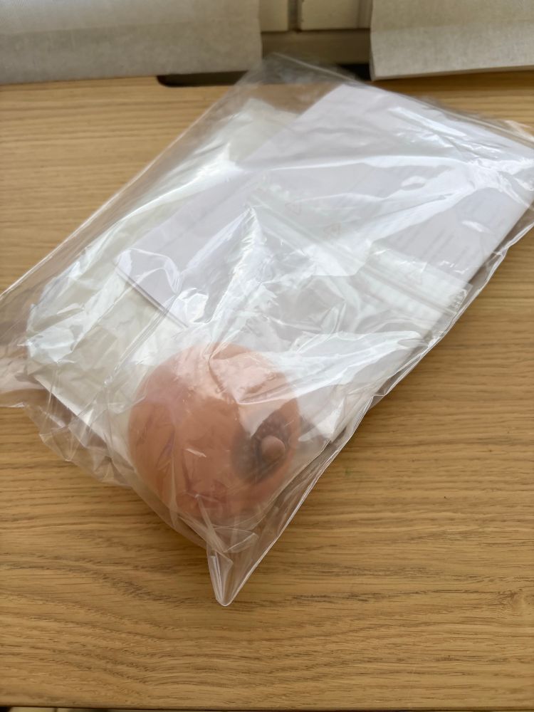 Une boule antistress en forme de sein dans un emballage plastique 
