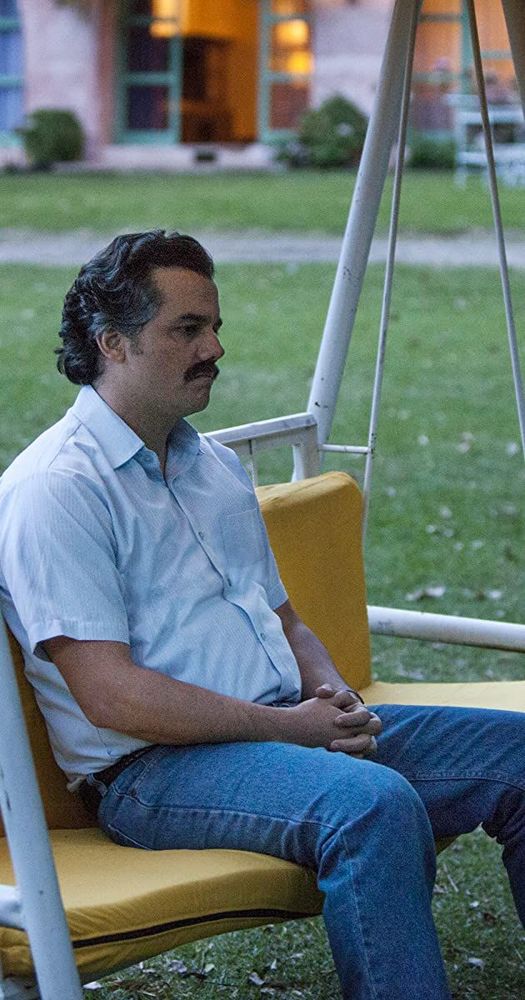 A man (Pablo Escobar?) sitting on a swing staring despondently 
