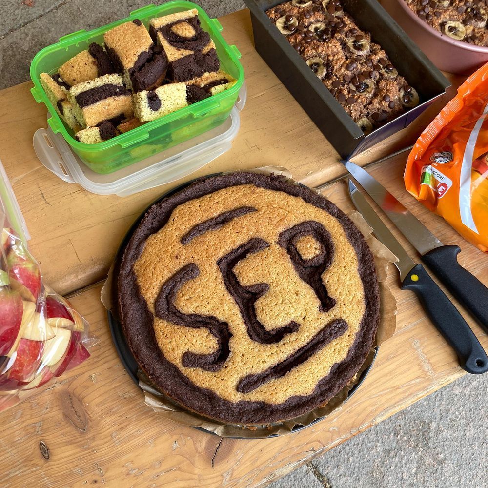 A homemade cake decorated with “SEP” in chocolate lettering, surrounded by other snacks and sweet treats that the students served at the farewell party.