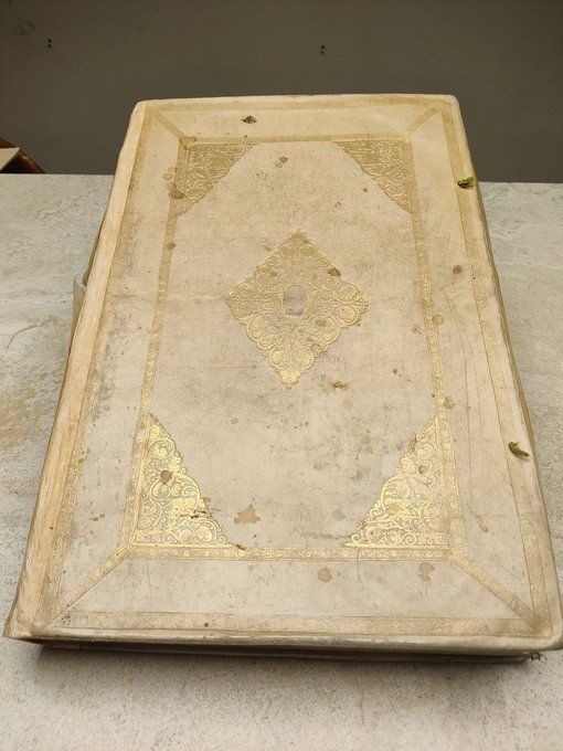 Very large pale vellum binding with plenty of gold accents, dramatically poised. 
