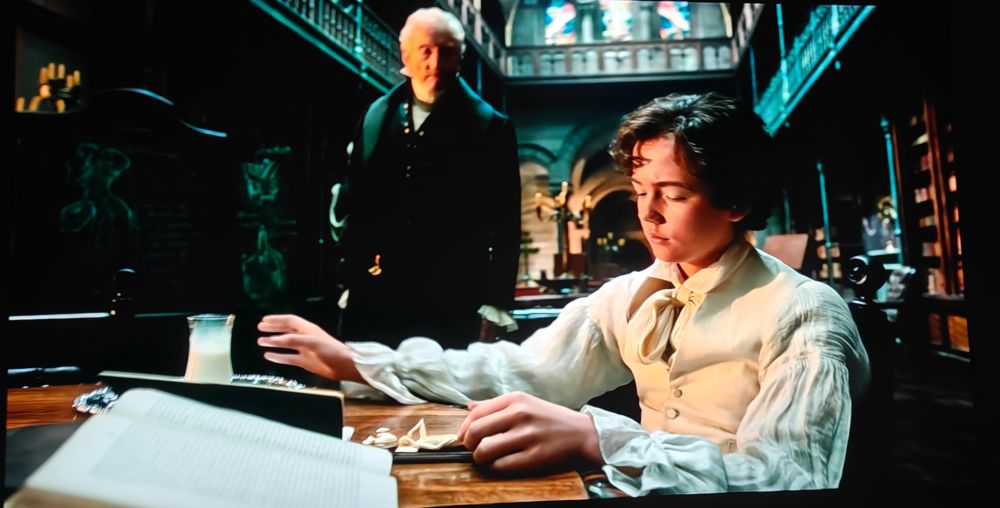 Charles Dance as Victor Frankenstein's father looming over him while studies an interactive ivory anatomical manikin. 