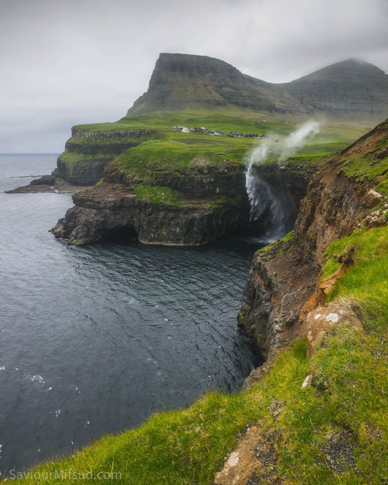 Waterfall going upwards because of strong winds at the village of Gásadalur, Faroe Islands