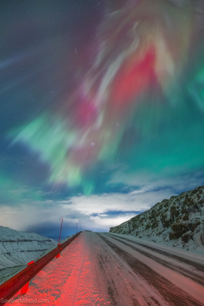 Northern lights at one of the mountain roads in the Faroe Islands on a snowy day.