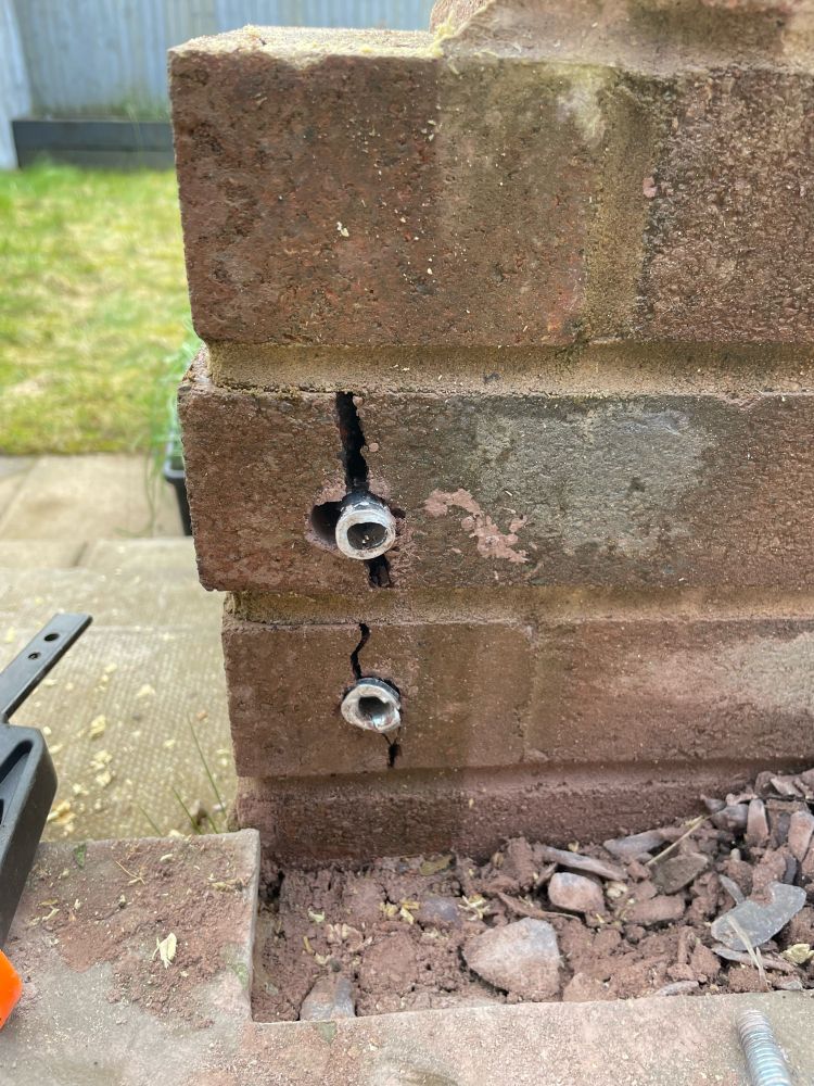 Broken wall bricks after failed attempt to insert mounting plugs