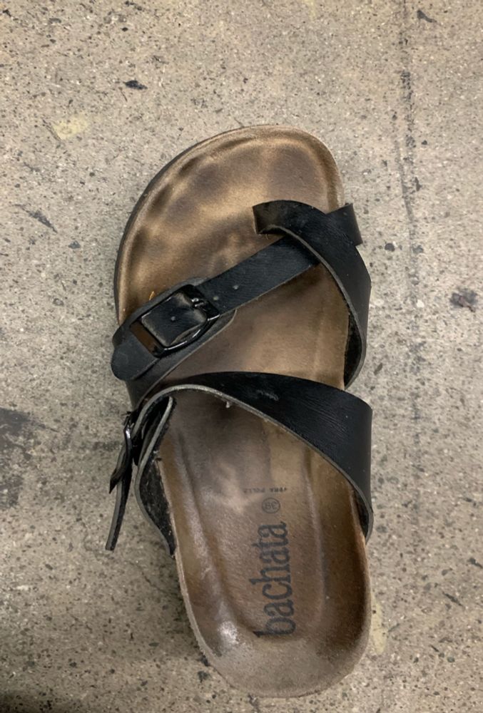 Photo of a sandal with a footprint in its sole, and within the print are human-shaped negative spaces
