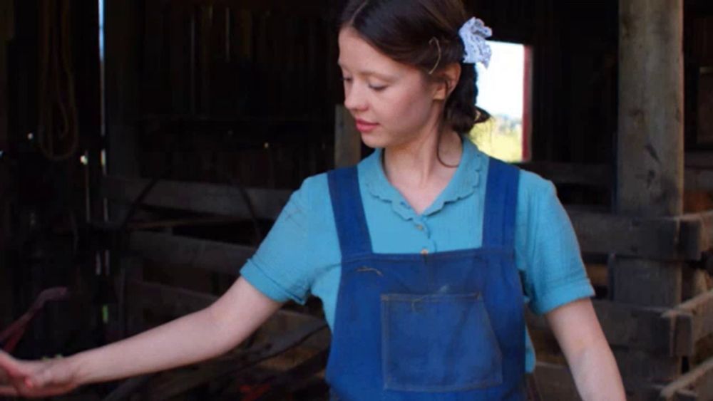 a girl wearing blue overalls and a blue shirt with a flower in her hair