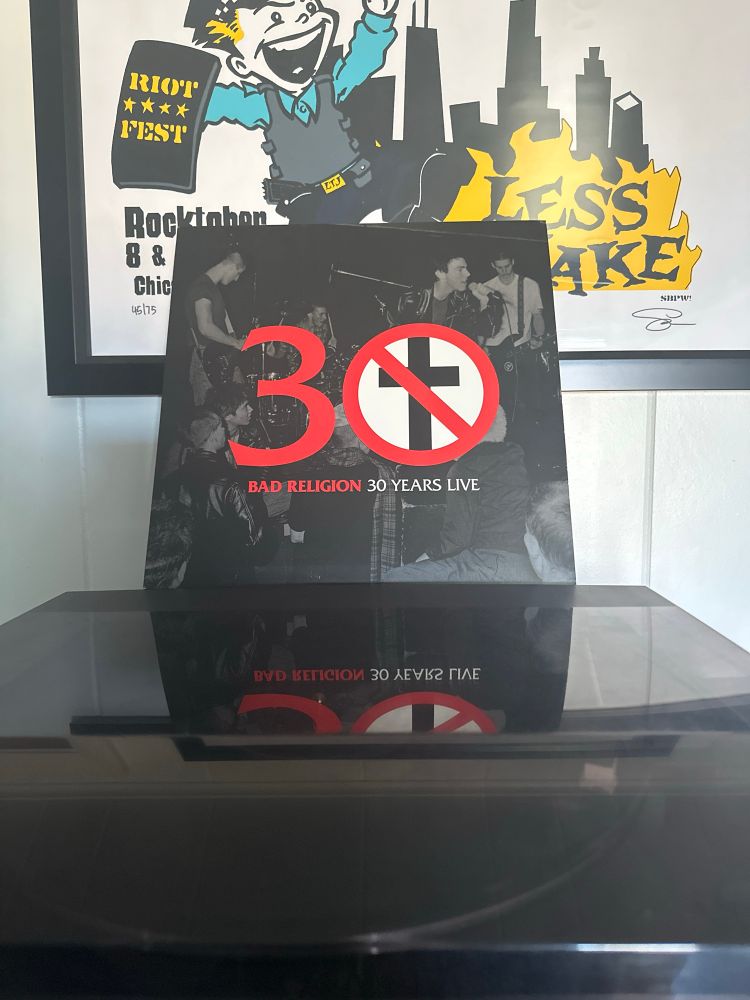Vinyl copy of Bad Religion’s 30 Years Live on a record player with a Less Than Jake poster in the background 