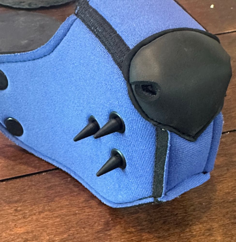 Photo of the muzzle of a pup hood with 3D printed spikes in the grommet holes 