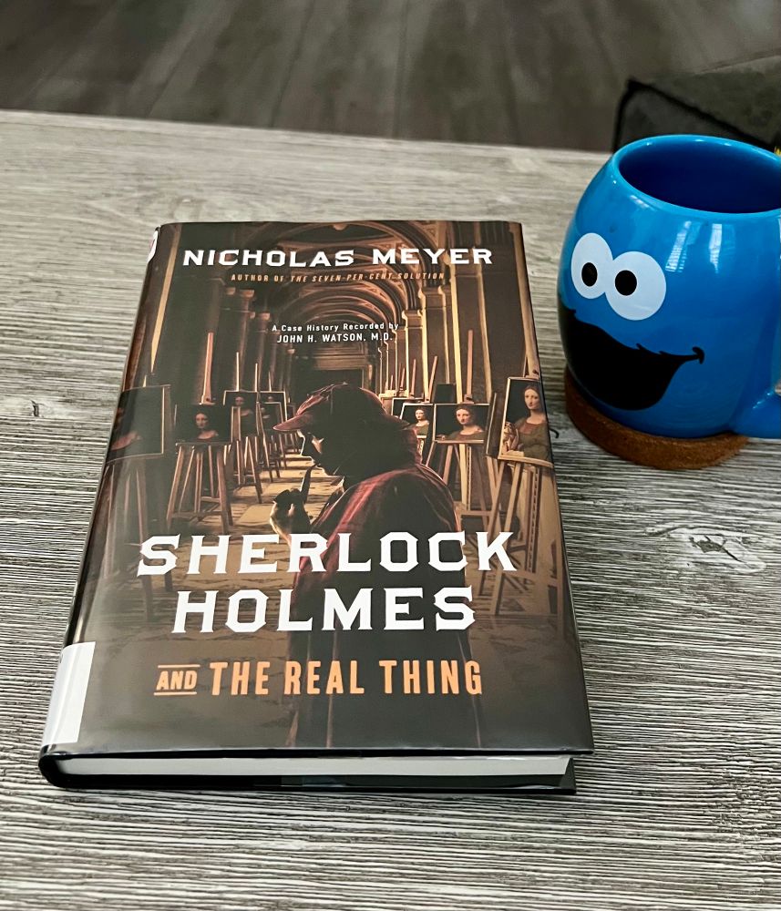 Book cover for “Mr Sherlock Holmes and the Real Thing” by Nicholas Meyer. Holmes, oddly attired with his deerstalker indoors, appears to be reviewing many portraits of the same subject. 
