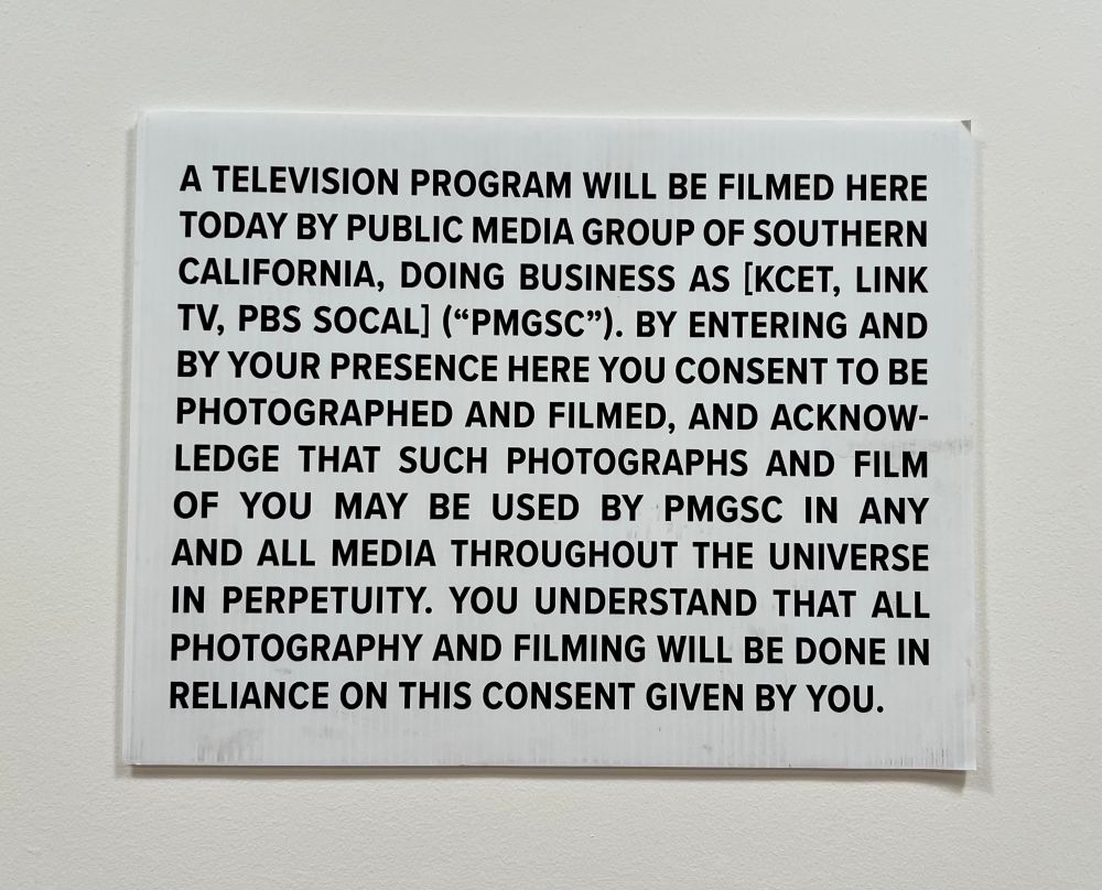 A notice declaring a show will be filmed here today. 
It says “A television program will be filmed here today by Public Media Group of Southern California, doing business as [KCET, Link TV, PBS SoCal] (“PMGSC”). By entering and by your presence here you consent to be photographed and filmed and acknowledge that such photographs and film of you may be used by PMGSC in any and all media throughout the universe in perpetuity, you understand that all photography and filming will be done in reliance on this consent given by you.”