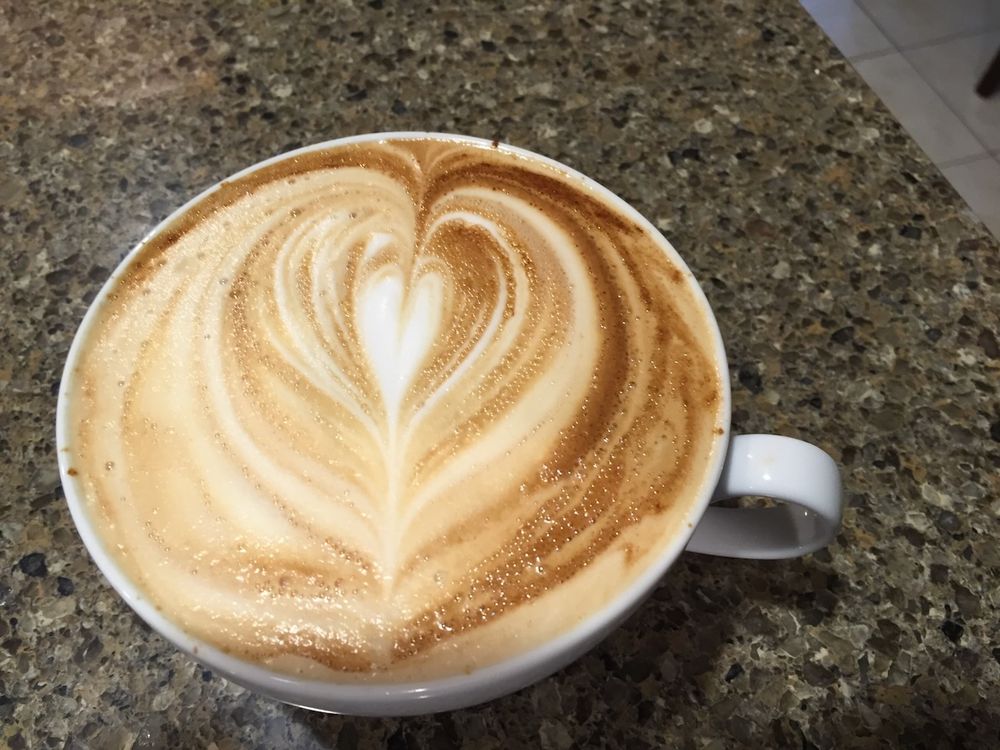 Latte in a white mug with a heart latte art pattern.